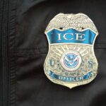 ICE Becomes NICE — Media Critics Outmaneuvered Close-up of an ICE officer badge on a black jacket