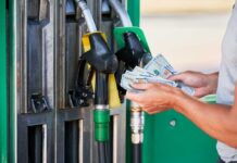 Person holding cash at a gas station while preparing to refuel