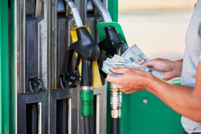 shutterstock_2509313045.jpg Person holding cash at a gas station while preparing to refuel