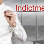 Jaw-Dropping Indictment: 30 Felonies! Businessman writing the word 'Indictment' in a modern office