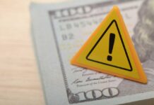 A warning sign placed on a hundred dollar bill