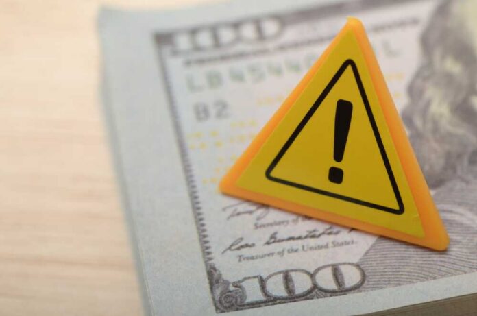 A warning sign placed on a hundred dollar bill