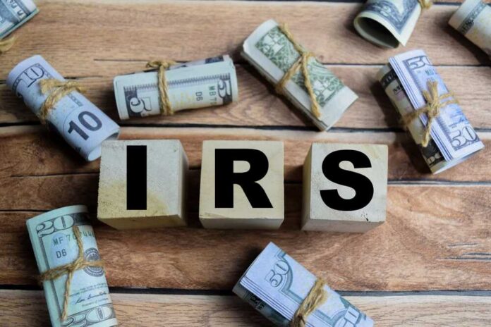 Wooden blocks spelling IRS surrounded by rolled currency notes