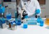 Scientist in a lab working with blue liquids and a microscope
