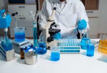 Scientist in a lab working with blue liquids and a microscope