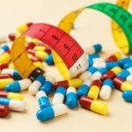 Colorful pills scattered around measuring tapes