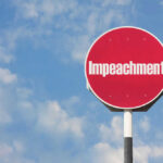 Red sign with the word Impeachment against sky