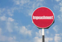 Red sign with the word Impeachment against sky