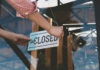 Person flipping closed sign on glass door