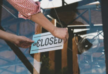 114-Year Coca-Cola Plant Shutting Down Person flipping closed sign on glass door