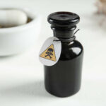 Black bottle labeled with a poison warning next to a mortar and pestle
