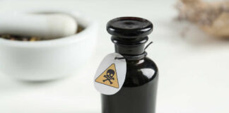 Black bottle labeled with a poison warning next to a mortar and pestle