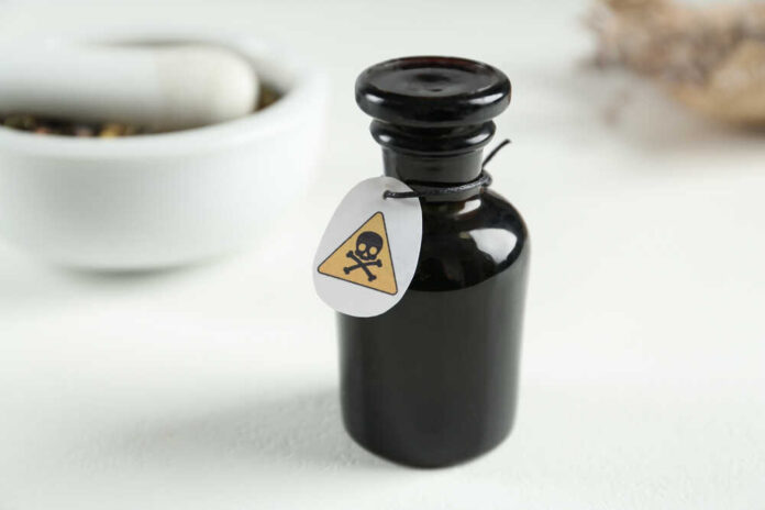 Black bottle labeled with a poison warning next to a mortar and pestle
