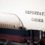 Close-up of a typewriter with a paper showing the words 'DEPORTATION ORDER'