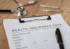 America’s Biggest Healthcare Insurer Blinks Health insurance form with a pen, stethoscope, and syringes on a wooden surface
