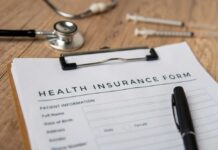 Health insurance form with a pen, stethoscope, and syringes on a wooden surface