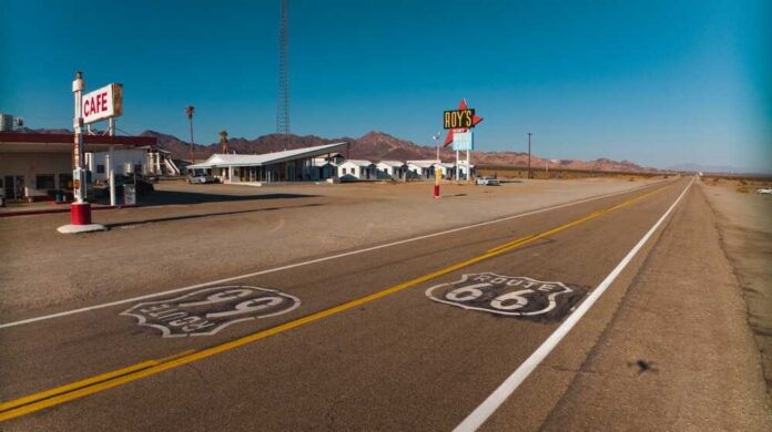 A deserted stretch of Route 66 featuring a cafe and vintage signs