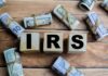IRS REFUNDS – Billions Up for Grabs! Wooden blocks spelling IRS surrounded by rolled currency notes