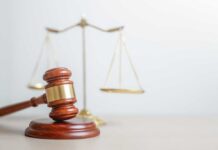 Massive Sentence Awaits Shooter in University Tragedy A wooden gavel in front of a balance scale symbolizing justice