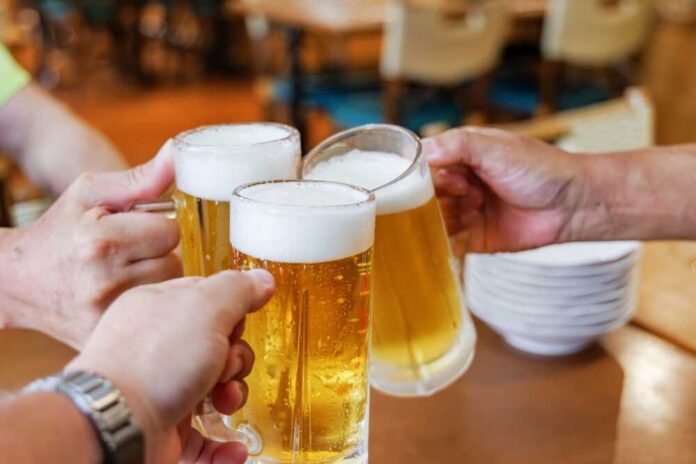 Delicious,,Cold,Beer,At,A,Restaurant Three hands clinking frothy beer mugs