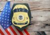 ICE Officer Charged — Video Exposed False Claims ICE officer badge displayed next to the U.S. flag