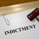 Communist Leader Faces U.S. Murder Indictment Gavel on a white paper with the word indictment on it.