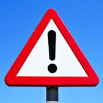VIDEO: Fireworks Disaster – 26 Dead in Blast A triangular warning sign with an exclamation mark against a blue sky
