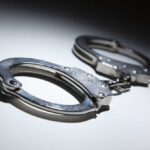 Livestreamer Faces Murder Charge Close-up of metallic handcuffs on a light surface