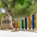 Debt Bomb Forces Painful Cuts Debt sack with rising financial graph bars.