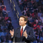 DeSantis Declares Victory Person speaking at podium in front of large audience.
