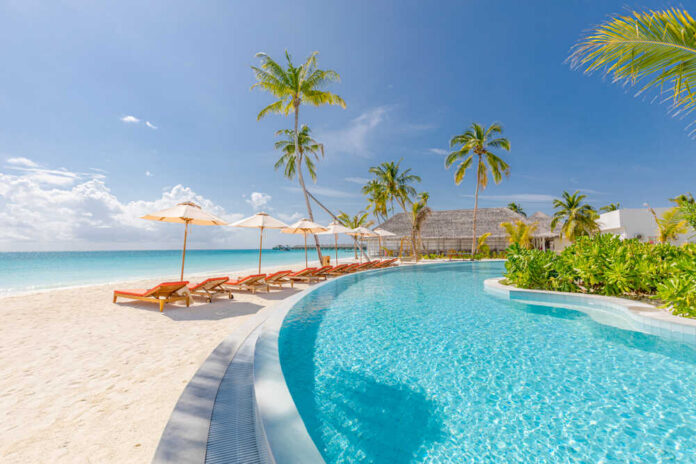 Outdoor,Tourism,Landscape.,Luxurious,Beach,Resort,With,Swimming,Pool,And A wooden pathway leading to the beach with restricted access tape and chairs in the background