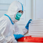Ebola Panic Grips Another Country?! Healthcare worker in protective gear disposing of waste
