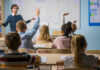 Culture War Hits Classrooms — Texas Goes Biblical Students raising hands in a classroom with a teacher.