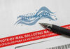 Banned Database Threatened Millions Of Votes? Vote-by-mail envelope with pen on top.