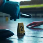 GPS Bombshell Impacts Potential Murder Case A detective examining evidence at a crime scene with markers on the floor