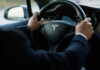 Person driving a Tesla car steering wheel