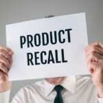 Person holding a sign reading product recall