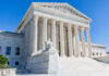 Supreme Court Nukes 91-Year Power Shield Supreme Court building with columns, fountain, and statue.