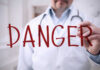 Doctor writing danger on transparent screen