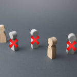 Candy Giant Ditches Blue State — 307 Jobs Torched Wooden figures representing people with red crosses indicating exclusion