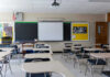 New School Hall Monitor: Drones? Empty classroom with desks, projector, and chalkboard.