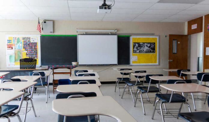 shutterstock_1751970764 Empty classroom with desks, projector, and chalkboard.