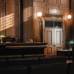 Supreme Court Snub Ends Trump’s Last Escape Interior of a courtroom with wooden paneling and green desk lamp