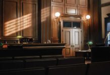 Supreme Court Snub Ends Trump’s Last Escape Interior of a courtroom with wooden paneling and green desk lamp