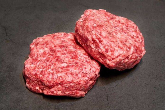 Raw,Beef,Burgers,On,Slate,Background Two raw ground meat patties on a dark surface