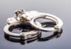 Famed Quarterback Cuffed, Arrested Close-up of metallic handcuffs on a reflective surface