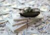 $37.5B? Pentagon’s Iran Math Explodes A toy tank placed on stacks of hundred-dollar bills