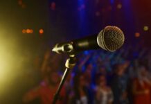 Shock Death Stuns Music World Close-up of a microphone in front of a blurred audience at a concert