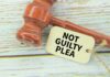 Convicted Killer’s Shocking Reversal A wooden gavel next to a tag that reads 'NOT GUILTY PLEA'