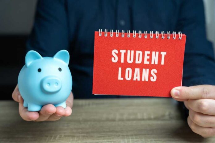 Student,Loans,Concept.,Financial,Aid,Provided,To,Students,To,Help A blue piggy bank and a red notebook displaying 'STUDENT LOANS'